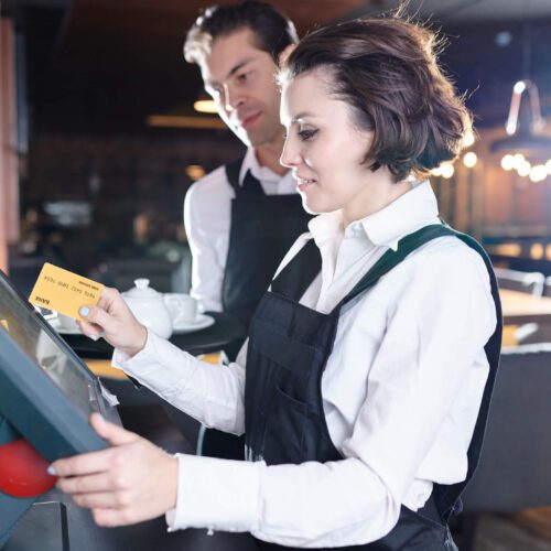 Content attractive young waitress with short hair swiping card through POS terminal while adding information