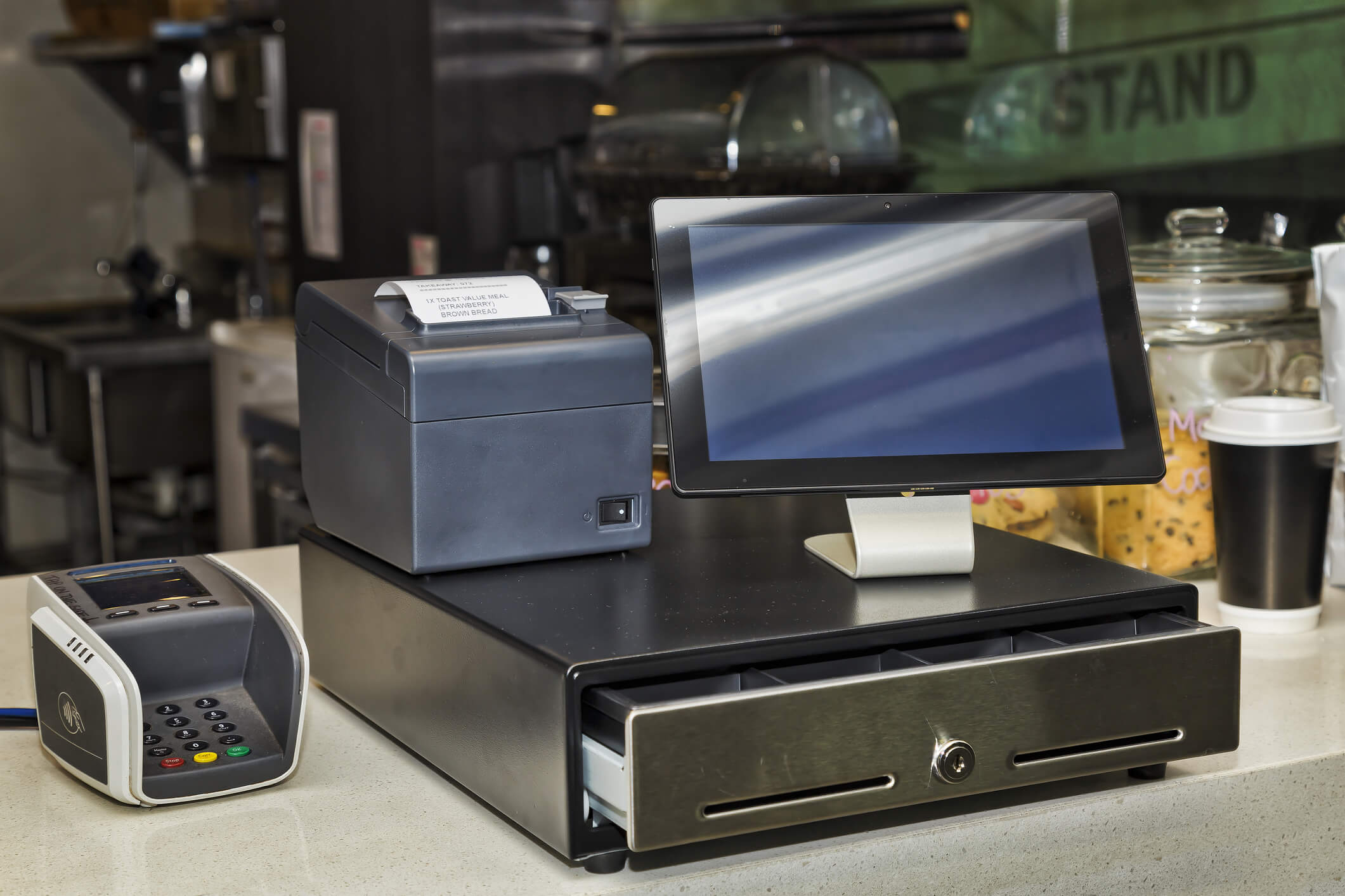 Cashbox, mobile printer, POS terminal and tablet PC on a counter in coffee shop providing innovative and efficient way to serve more customers