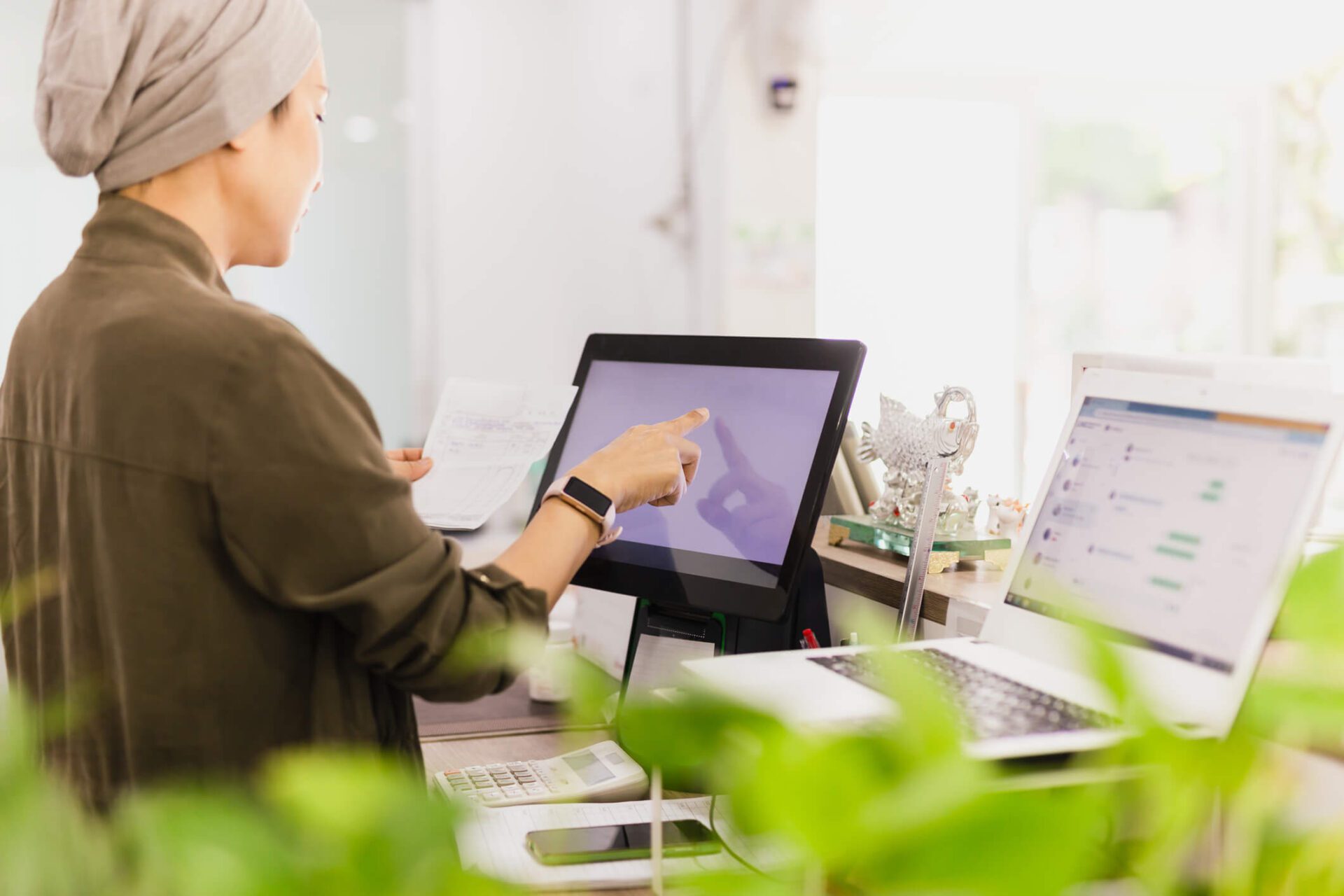 Female cashier operating cash register with order in her hand at restaurant